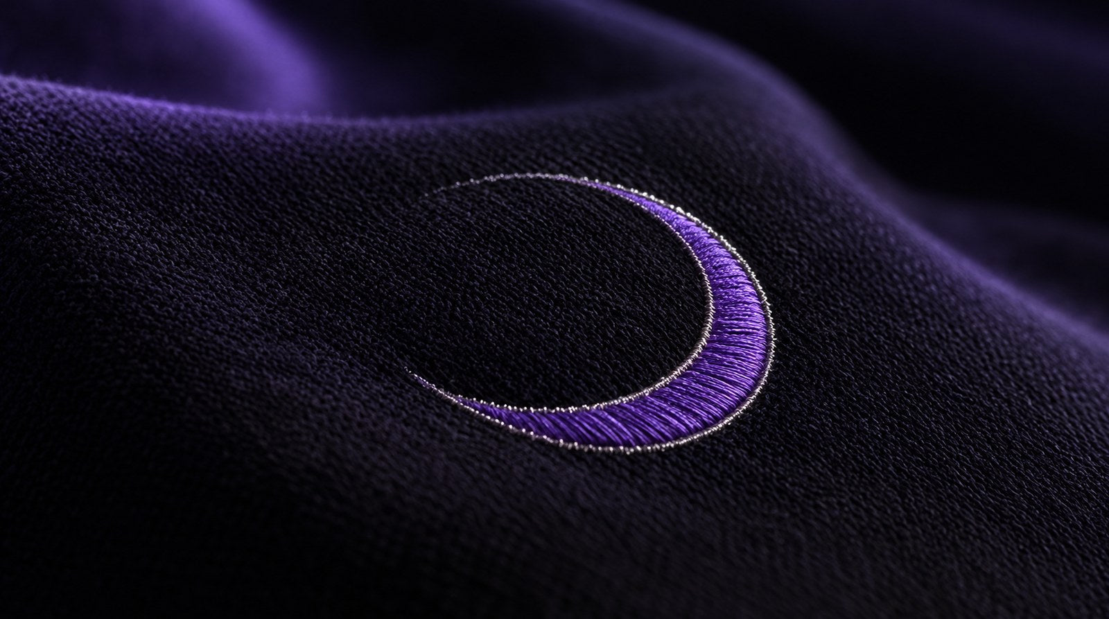Macro of violet crescent embroidery on black knit